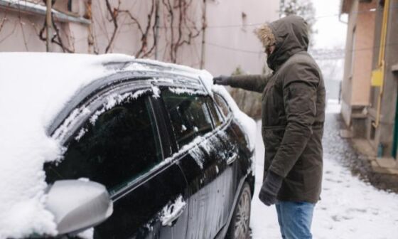 Jak odśnieżyć samochód? Mężczyzna odśnieżający auto